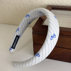 Detailed view of the handmade label and blue bow pattern on the fabric headband