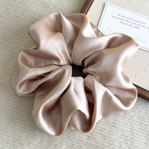 Close-up of champagne gold oversized satin scrunchie with elegant silk texture and soft folds