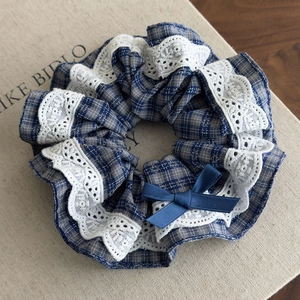 Detail of British style blue plaid scrunchie with white lace trim and satin bow tie