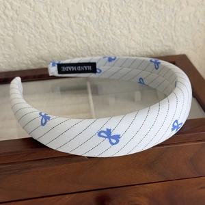 Detail showing blue striped bow headband texture with Hand Made woven label on wood box