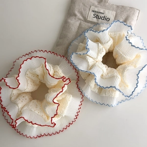 Close-up of red and blue lace ruffles on oversized scrunchies with intricate hollow patterns