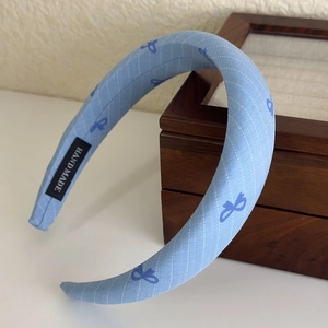 Detail of blue striped headband with bow print and handmade label on wooden box