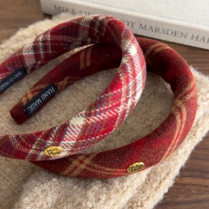 Detail of red plaid sponge headband featuring a hand-made label and metal charm