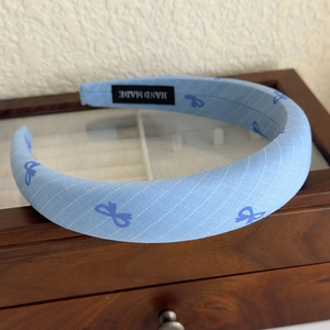 Detail of light blue diagonal stripe headband with navy bows and handmade label