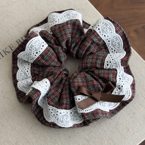 Detailed texture of British style red plaid scrunchie with lace trim and ribbon bow