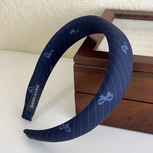 Detail of blue striped headband with bow pattern and handmade label on wood background