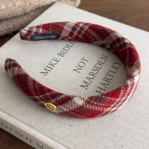 Detail of red and white plaid headband showing handmade label and golden metal plate