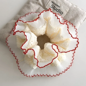 Macro detail of vintage layered lace scrunchie with red scalloped embroidery edge