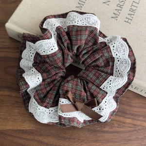 Detailed shot of British style plaid scrunchie with lace edges and a silk bow