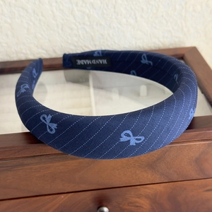 Detail of blue diagonal stripe headband with handmade label on wooden display box