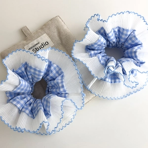 Detalle de dos coleteros de cuadros azules y encaje blanco con bordes de volantes finos