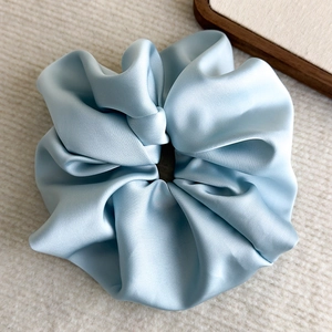 Detailed view of large light blue satin scrunchie with a soft glossy silk texture
