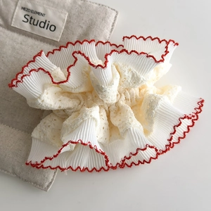 Close-up of vintage pleated fabric hair scrunchie with lace details and red scalloped edges