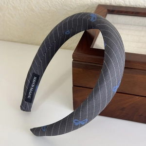 Detailed shot of handmade blue striped bow headband with premium grey fabric texture