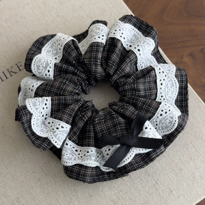 Detail of British style brown plaid scrunchie with lace edges and a black bow
