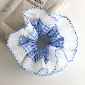 Detalle de coletero de cuadros azules con capas de tul plisado y borde bordado ondulado