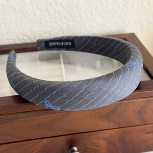 Close-up of handmade blue bow headband with diagonal stripes on a wooden jewelry box