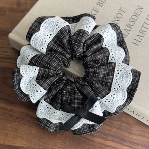 Detailed macro view of the vintage brown plaid scrunchie with white lace edges and a black bow