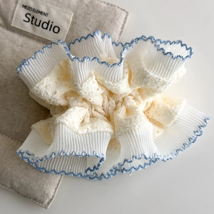 Detail of vintage cream lace scrunchie with pleated fabric and blue wavy stitching