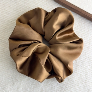 Detailed macro view of the glossy bronze satin scrunchie fabric and its rich silk texture