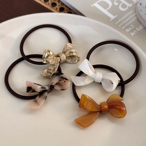 Set of four elegant acetate bow hair ties in tortoiseshell, pearl, and amber finishes