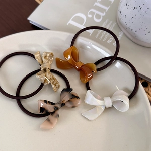 Set of four elegant acetate bow hair ties in amber, marble, and tortoiseshell patterns