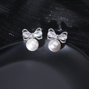 Macro shot of silver bow knot earrings with micro-set zircons and round white pearls