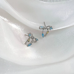Boucles d'oreilles nœud en argent avec zircons bleus et jaunes sur soie blanche