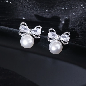 Macro shot of silver bow earrings with pear-cut zircon and elegant white round pearls