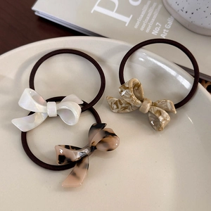 Three-piece acetate bow hair ties in marble, tortoiseshell, and pearlescent white patterns