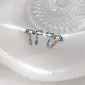 Gros plan de boucles d'oreilles nœud en argent avec zircons bleus et jaunes