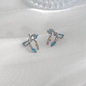Détail de boucles d'oreilles nœud argentées avec zircons marquise bleus, jaunes et clairs