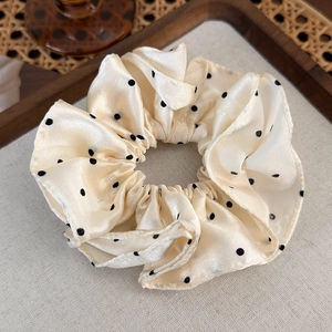 Détail du chouchou en satin crème à pois avec texture soie et plis élastiques
