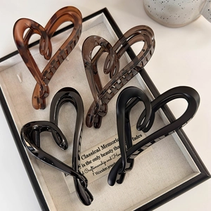 Détail de quatre pinces à cheveux en forme de cœur en écaille, marron et noir mat