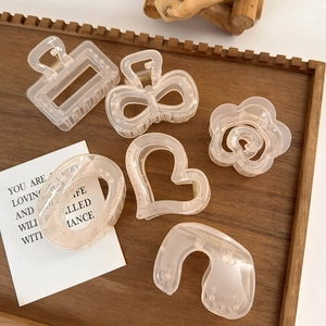 Set of translucent peach pink hair claws in various shapes displayed on a wooden tray