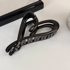 Détail d'une pince à cheveux noire en forme de cœur avec une finition brillante