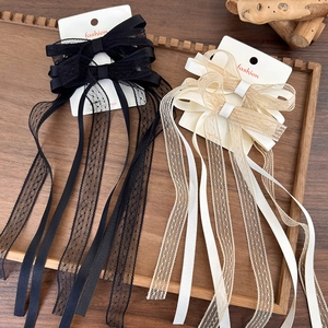 Detailed close-up of double-layered lace bow hair clips with long ribbons on display card