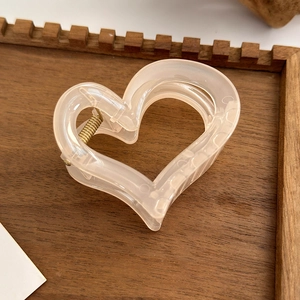 Detailed close-up of a heart-shaped translucent pink hair claw clip on a wooden surface