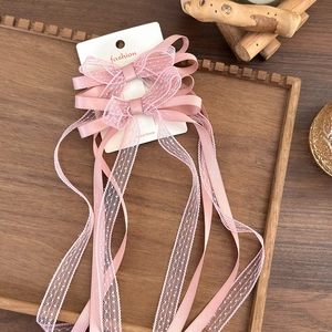 Detail of pink satin lace bow hair clips with long ribbons on a wooden tray