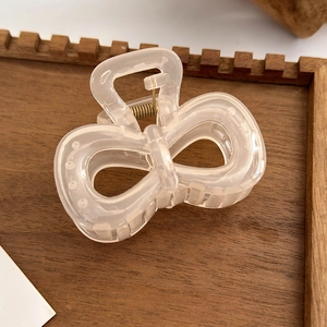 Detail of translucent camellia bow hair claw with gold spring and non-slip teeth