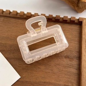 Detail of translucent champagne hair claw clip with golden metal spring on wooden tray