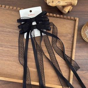 Detail of black lace bow hair clip with long ribbons on a decorative wooden tray