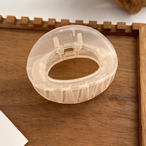 Close-up of translucent camellia bow hair claw clip showing resin texture and metal spring