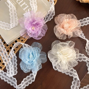 Detail of lace flower chokers with ribbons in soft pastel colors on a wooden surface