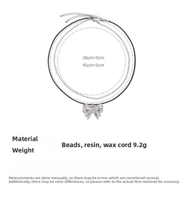 Detail view of double-layer beaded necklace with silver bow pendant and size specifications