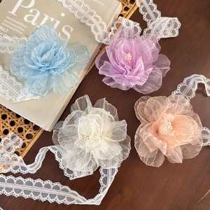 Detail of multi-layer organza flower chokers with lace trim and pearl centers
