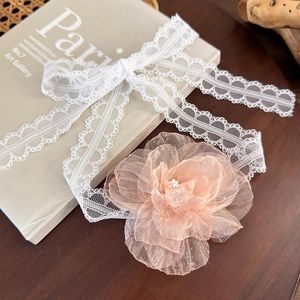 Detailed close-up of lace ribbon and champagne organza flower with pearl centerpiece