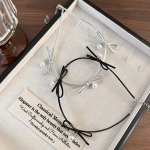 Détail d'un ensemble choker nœud avec perles sur cordon cuir dans une boîte à bijoux