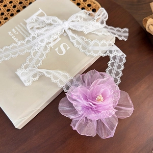 Detail of white lace choker with purple mesh flower and pearls on vintage book