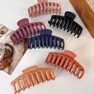 Detail of 6 matte large shark hair claws in multiple colors on a wooden tray